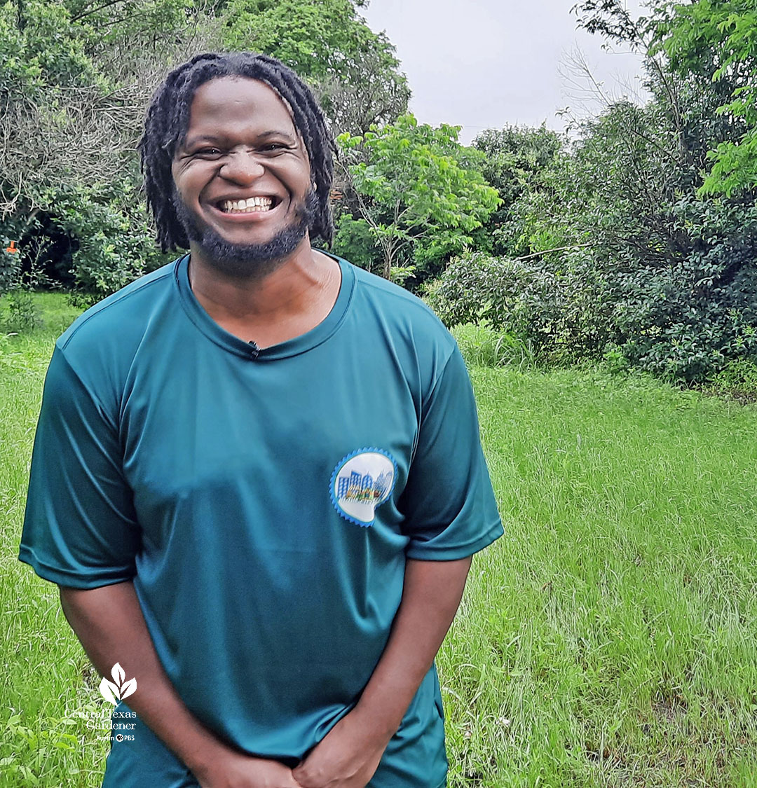 smiling young man in grassy lot surrounded by trees 