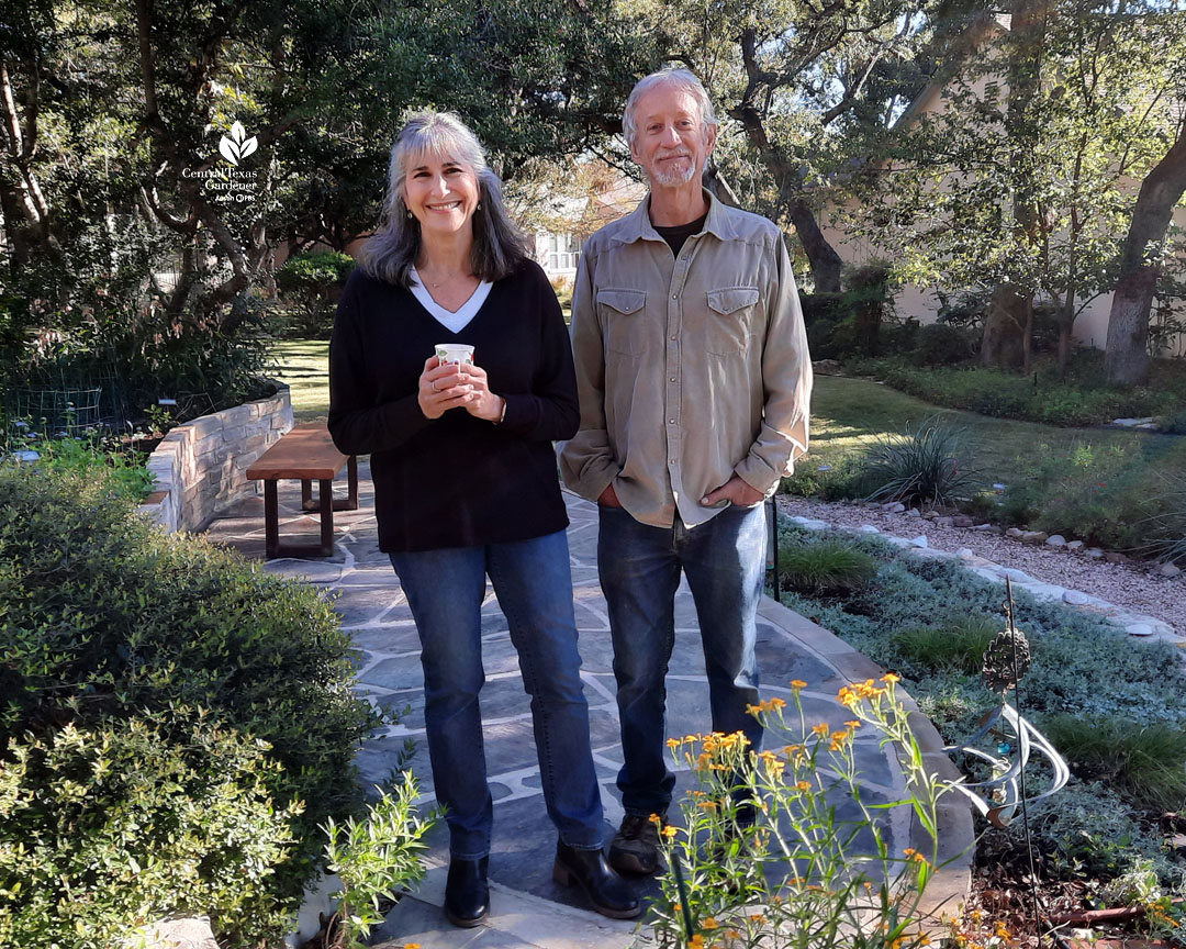 smiling man and woman on blue flagstone walkway in front of house and garden