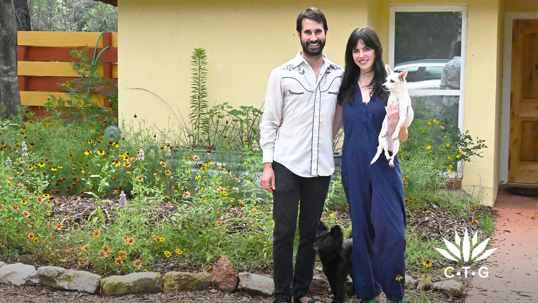 man and woman and two small dogs in front of garden against their house