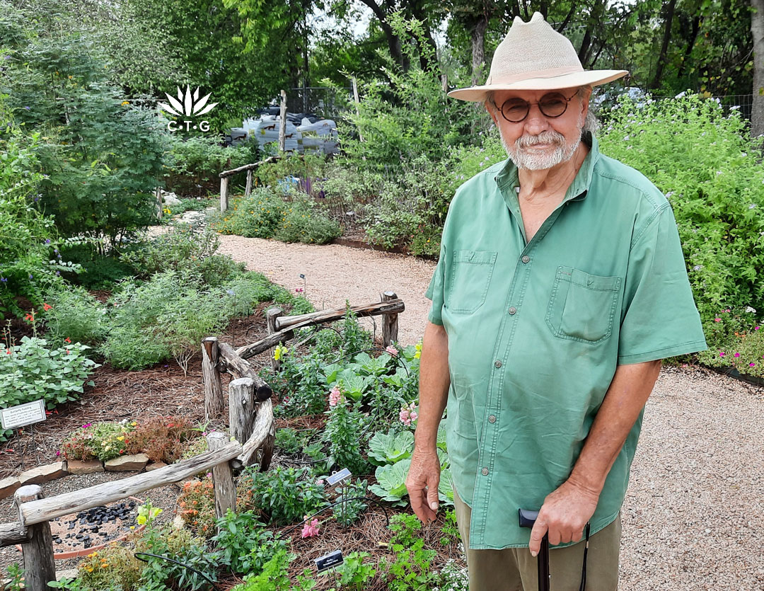 man with cane standing in colorful garden 