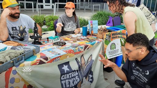 man and woman at table with promotional materials talking to students