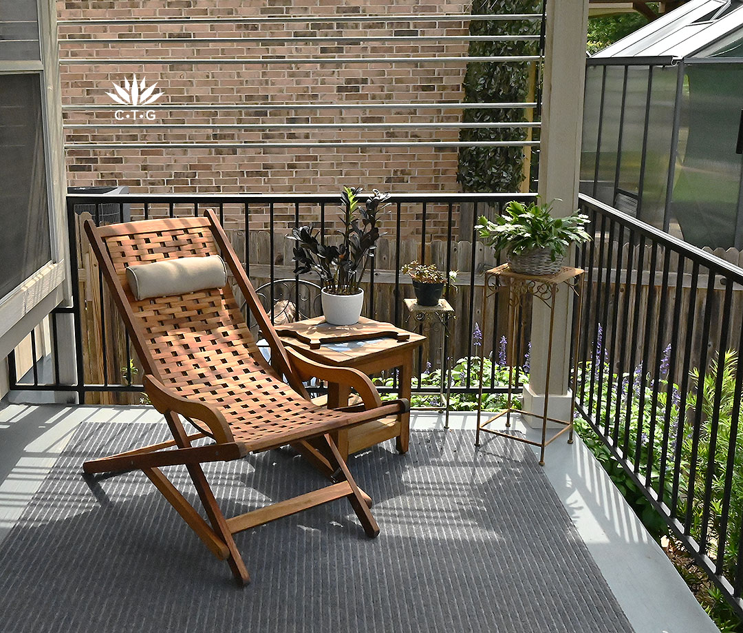 outdoor chair and table on rug of patio deck; electrical conduit frames one side