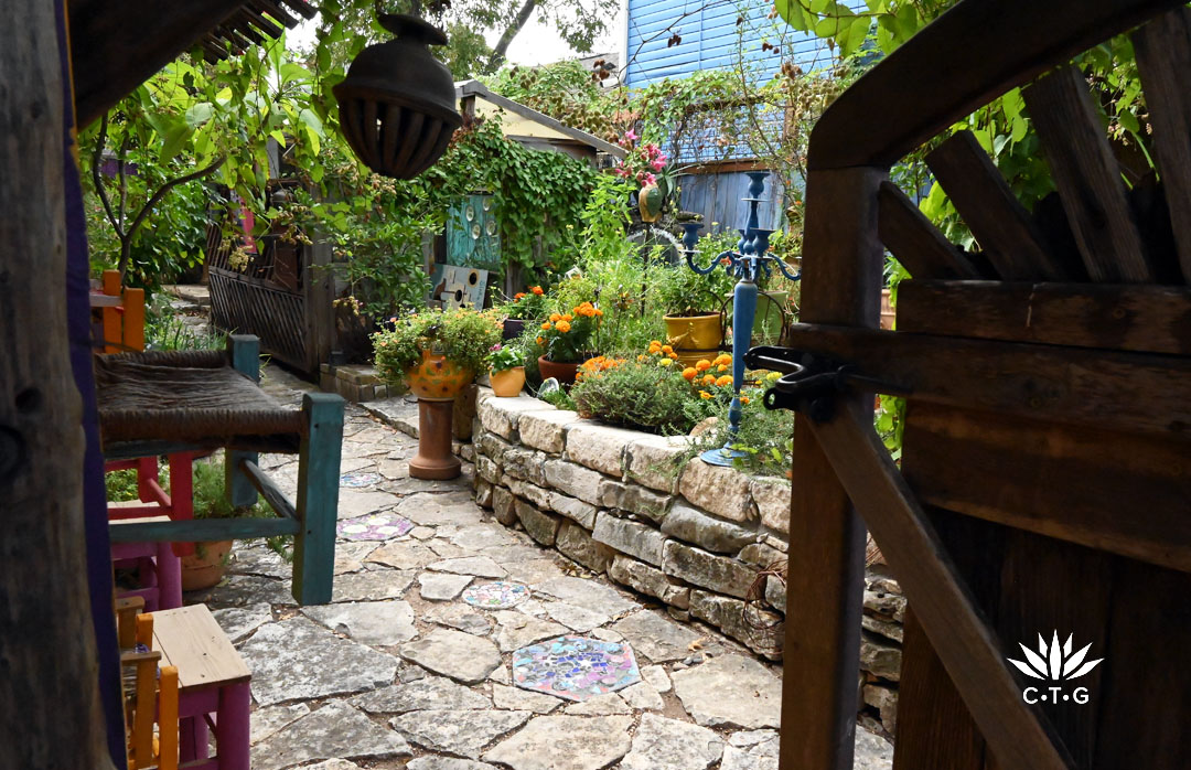 wooden gate to garden of raised stone beds on flagstone