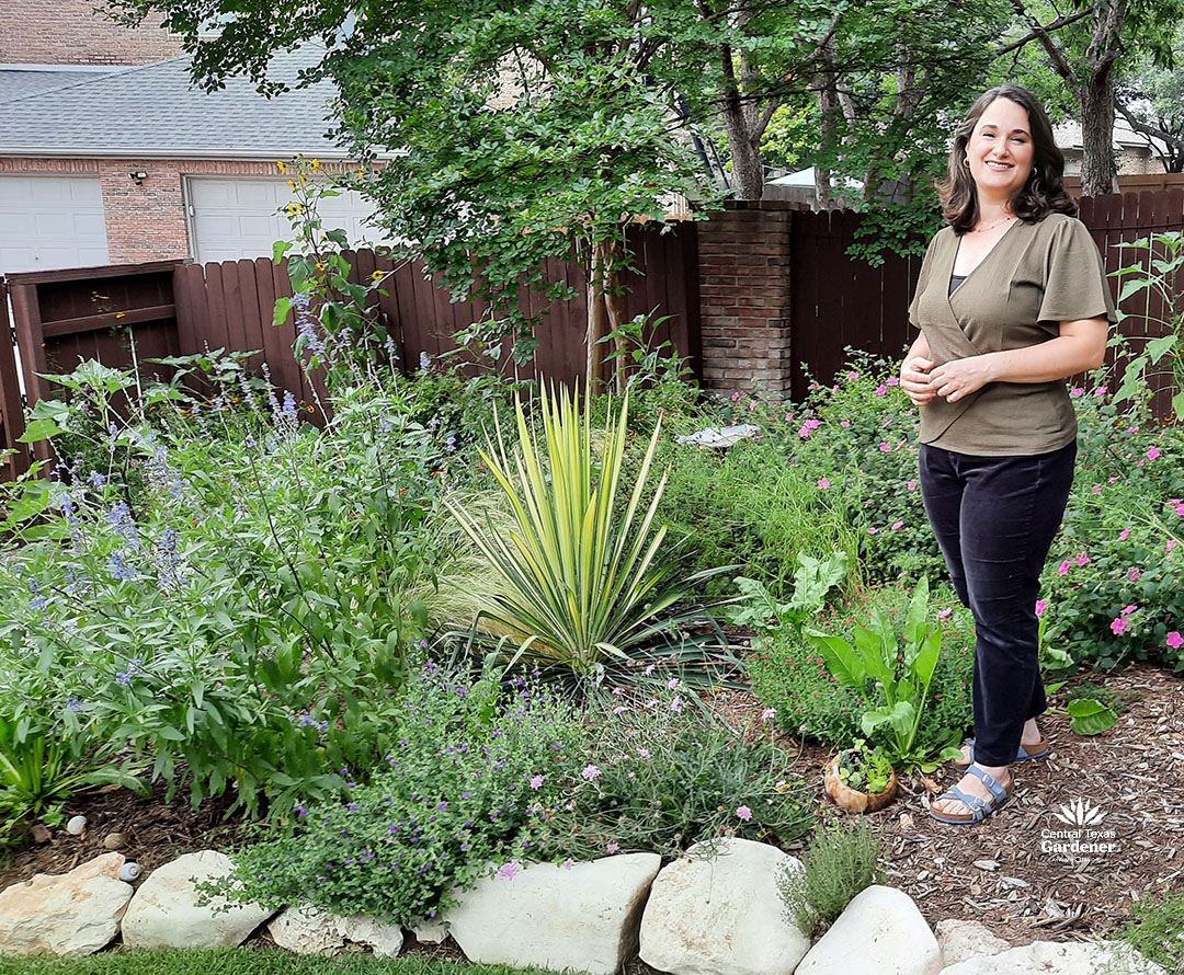 woman standing in garden with yucca and flowering perennials 