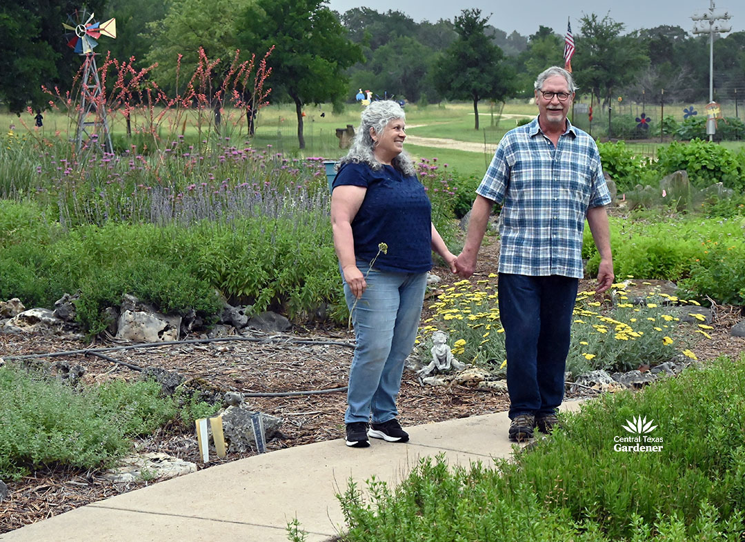 man and woman holding hands in front yard of perennial garden 
