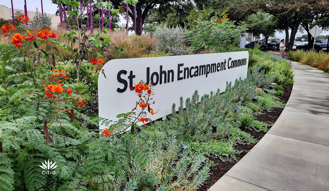 stone sign: St. John Encampent Commons surrounded by colorful perennials and silveery succulents