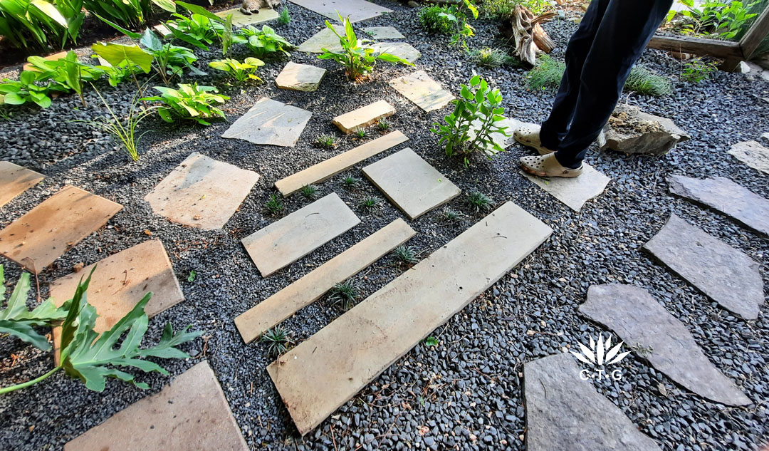 sand colored pavers cut into different lengths and shapes on black gravel 